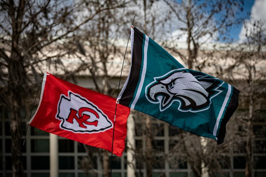 Kansas City Chiefs and Philadelphia Eagles team flags flying side by side against a winter sky.